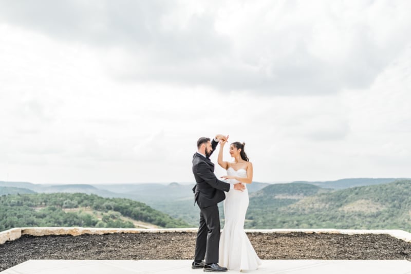 A bride and groom dance on the stone overlook at The Chapel at Wimberley with Hill Country valleys stretching to the horizon
